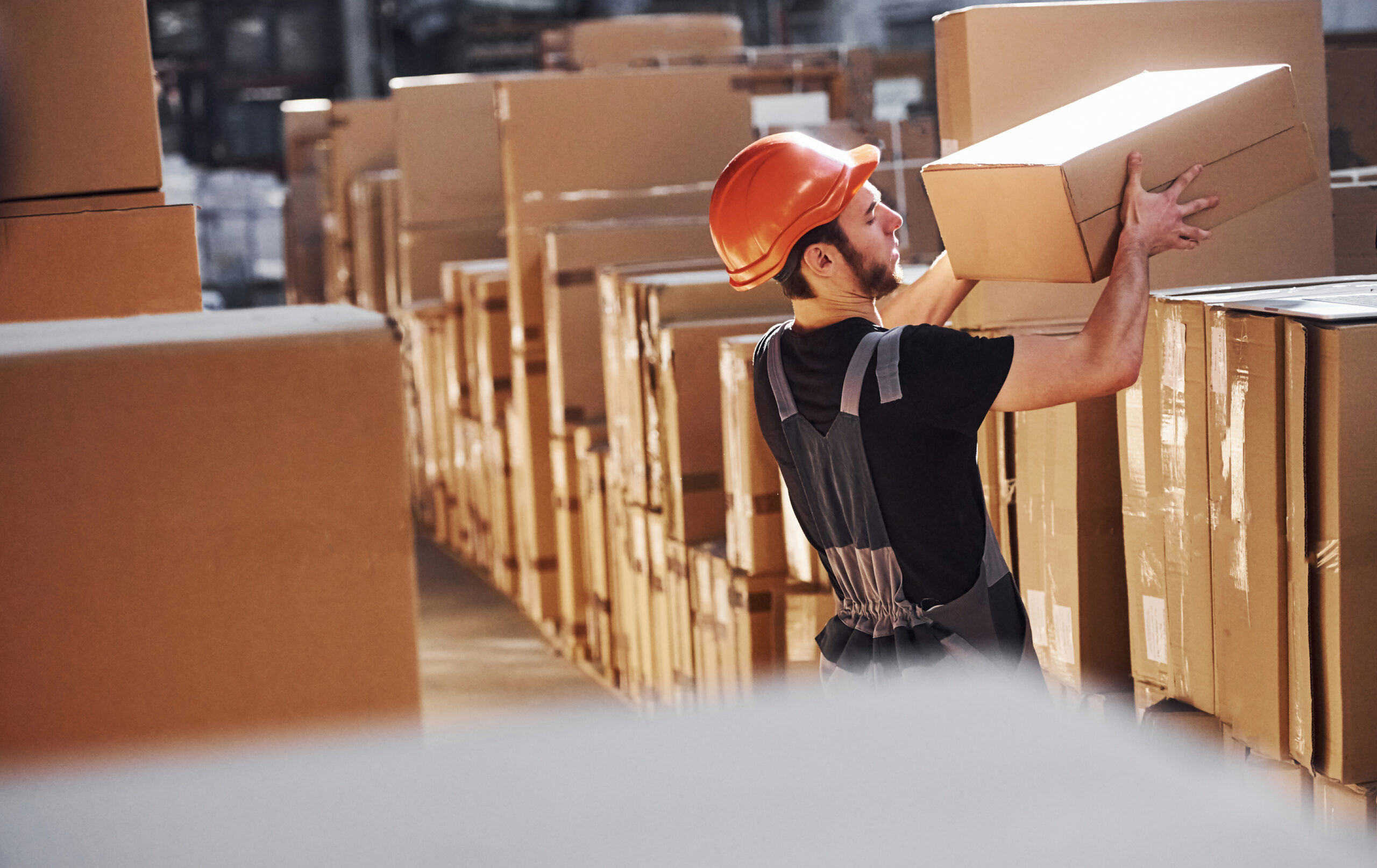 Young storage worker in warehouse in uniform busy with some work.